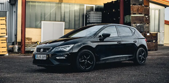 Siyah bir SEAT Leon aracı sanayi bölgesinde park halinde.