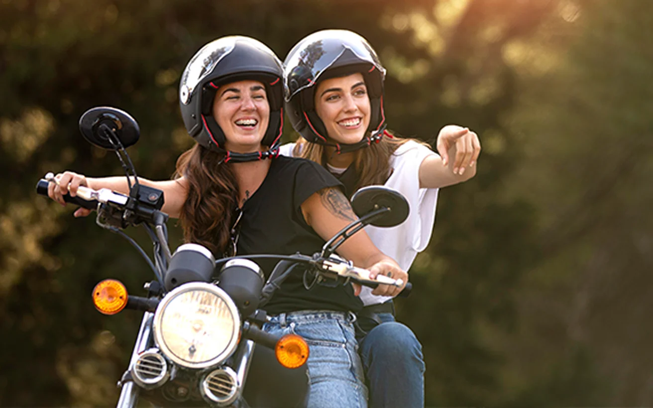 Orman yolunda yeşil scooter kullanan mutlu çift. Güvenli seyahat ve motosiklet sigortası konsepti.