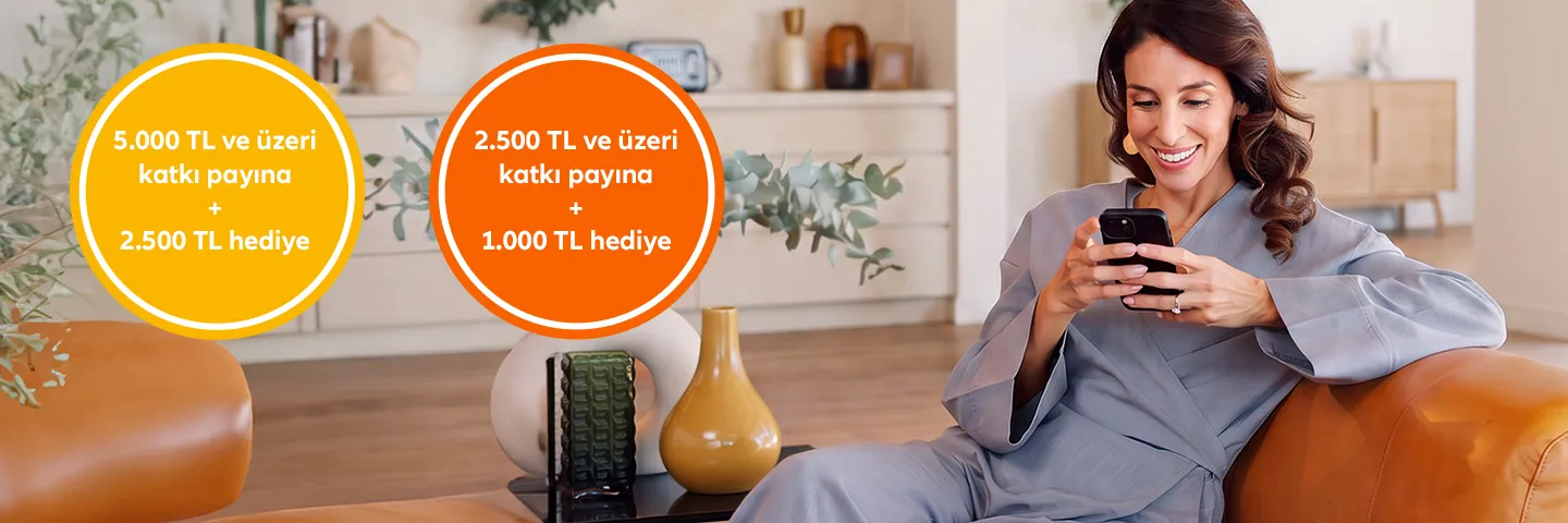 Görsel, Allianz BES katkı payı kampanyasını tanıtan bir afiş. Bir kadın, modern bir oturma odasında deri bir koltukta otururken telefonuna gülümseyerek bakıyor. Görselin sol üst köşesinde iki dairesel rozet var. Sarı rozette "5.000 TL ve üzeri katkı payına + 2.500 TL hediye", turuncu rozette ise "2.500 TL ve üzeri katkı payına + 1.000 TL hediye" yazıyor. Arka planda şık bir konsol, bitkiler ve dekoratif objeler görülüyor. Oturma odası sıcak ve davetkar bir atmosfere sahip.