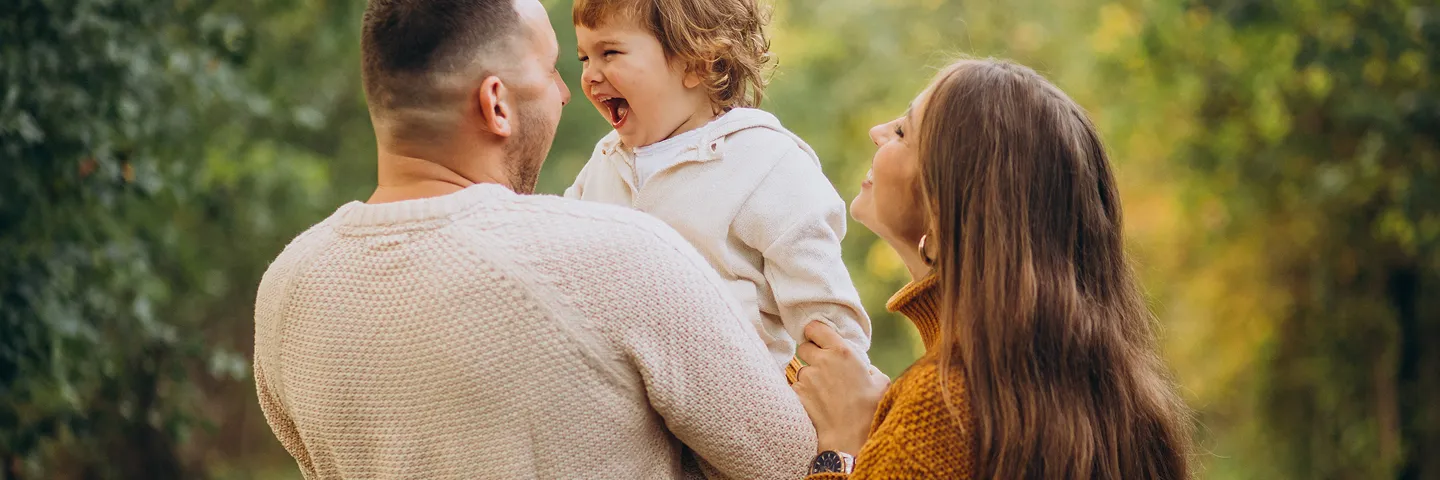 Doğada küçük bir çocukla neşeyle gülümseyen anne ve baba