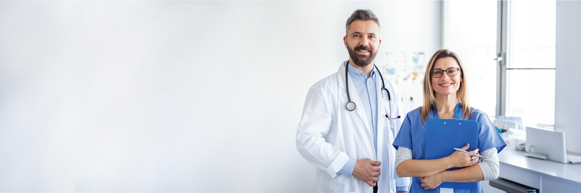 Allianz Türkiye güvencesiyle kameraya gülümseyen uzman erkek doktor ve dosya tutan kadın sağlık çalışanı.