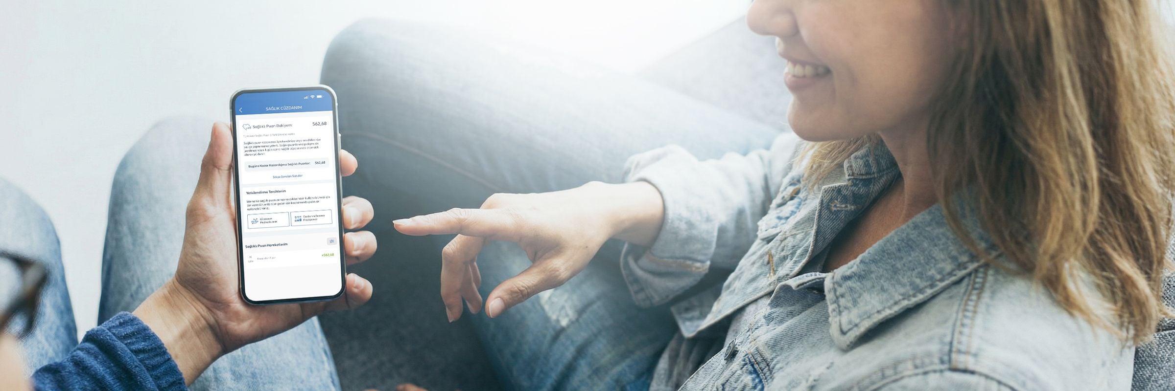 Akıllı telefondan Allianz Sağlık Cüzdanım uygulamasına ve puanlarına bakan gülümseyen kadın.