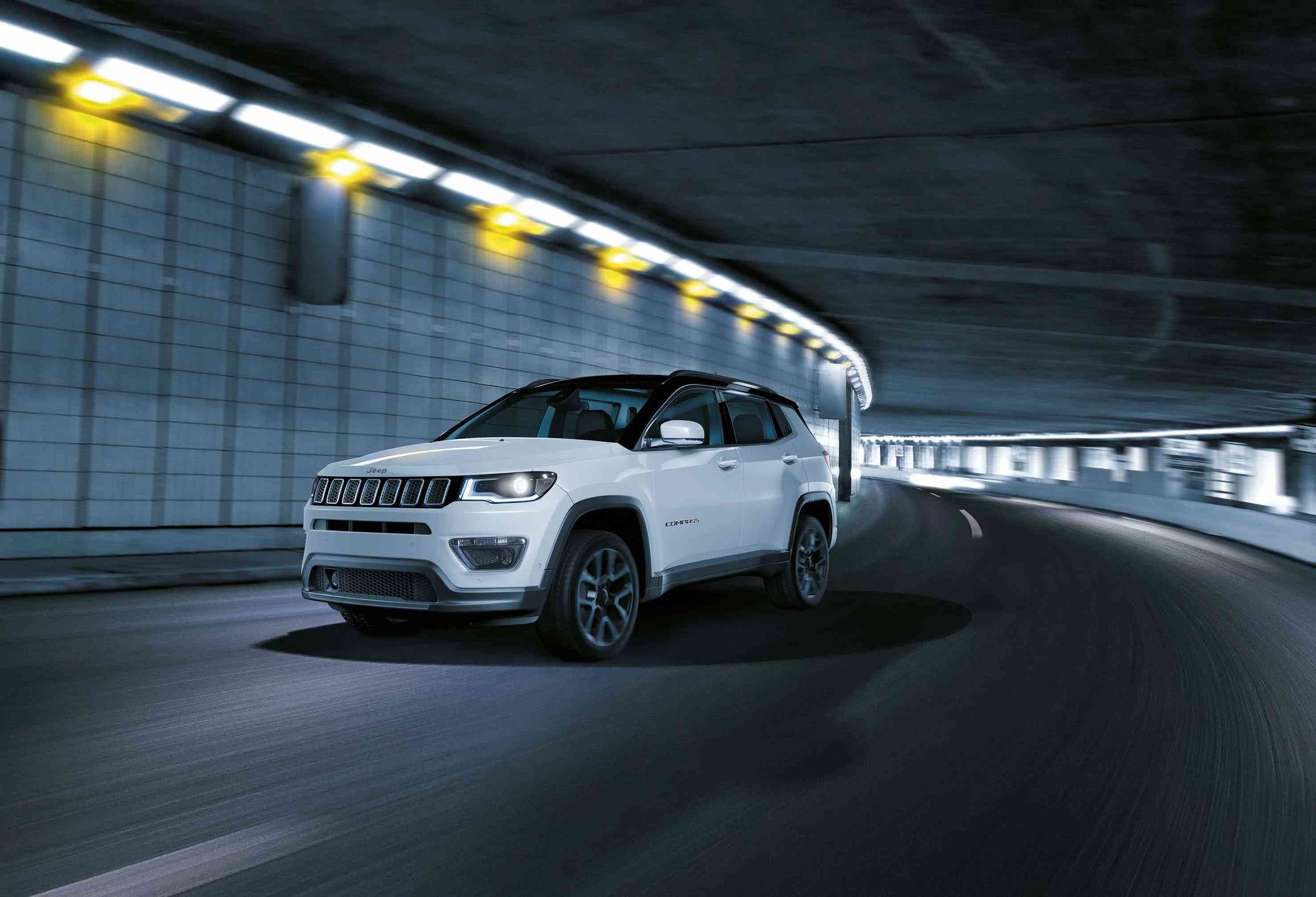 Modern bir tünelde hızla ilerleyen şık beyaz Jeep Compass SUV. Dinamik sürüş ve aydınlık tünel ortamı dikkat çekiyor.