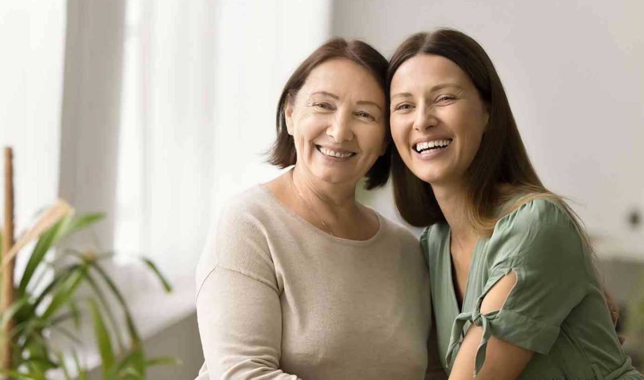 Gülümseyen anne ve kızı birbirlerine sarılmış, aile bağlarını ve mutluluğu simgeliyorlar.