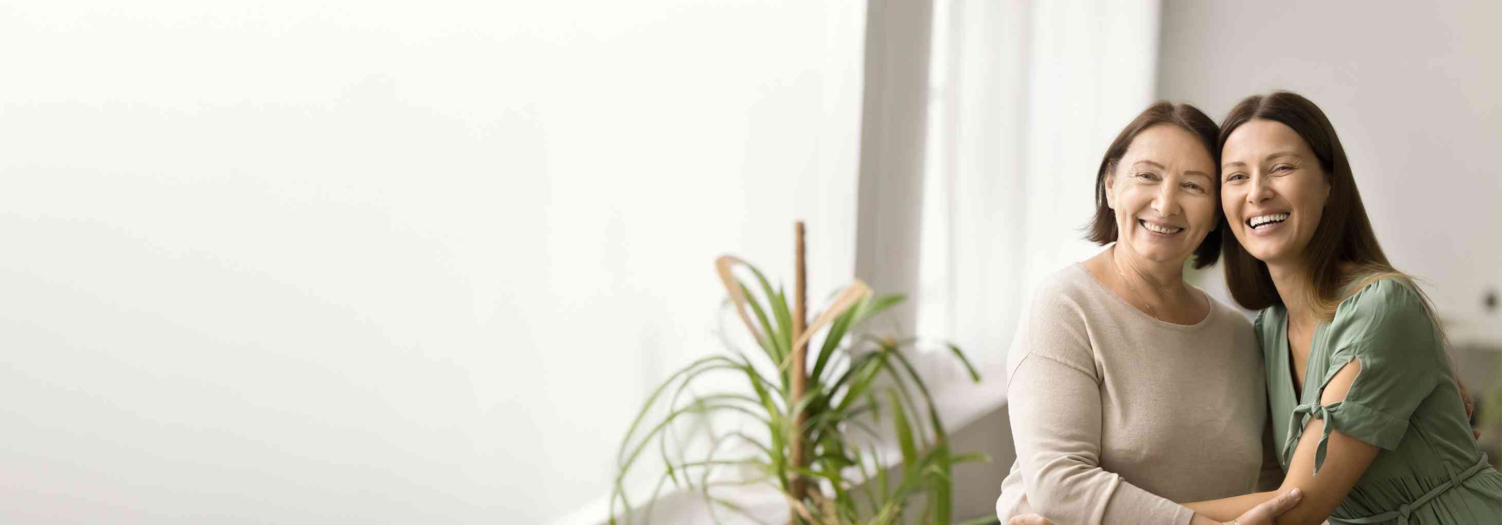 Gülümseyen anne ve kızı birbirlerine sarılmış, aile bağlarını ve mutluluğu simgeliyorlar.