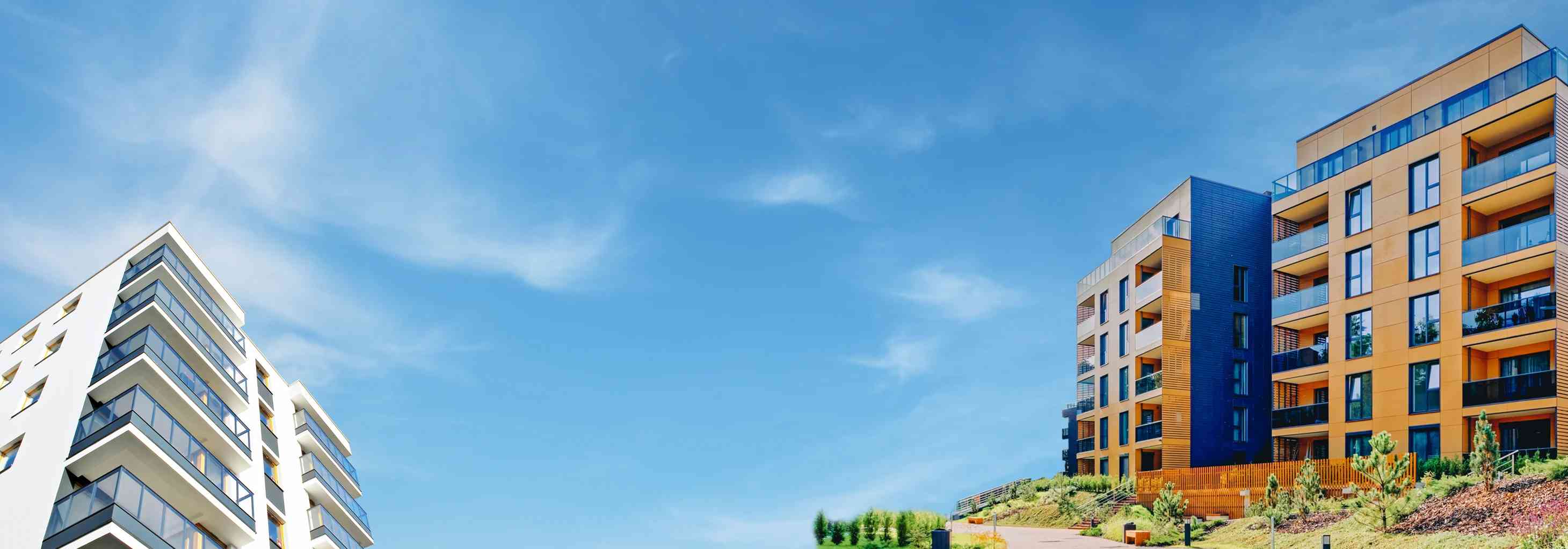 Modern apartman binaları ve masmavi gökyüzü altında yeni konut projeleri. Allianz ev sigortası için ideal.